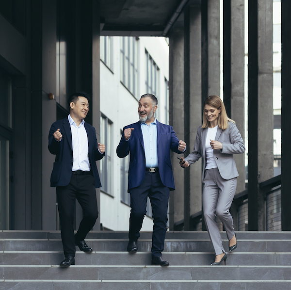 Happy business people walking out of a building in the city